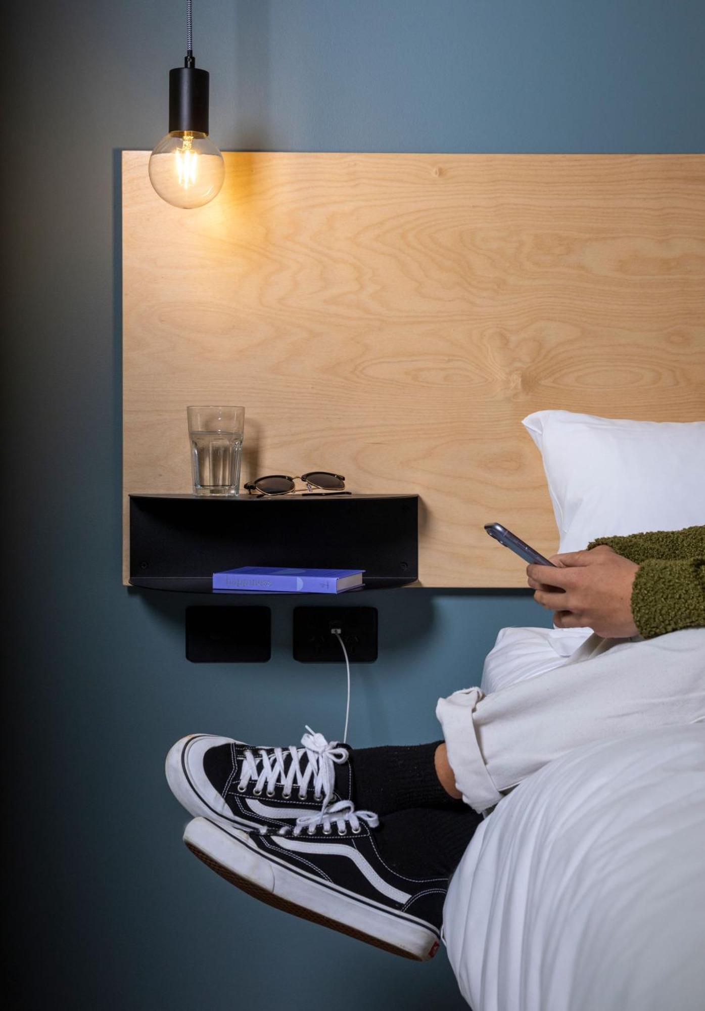 Lylo Auckland Hotel ห้อง รูปภาพ A phone being used in bed